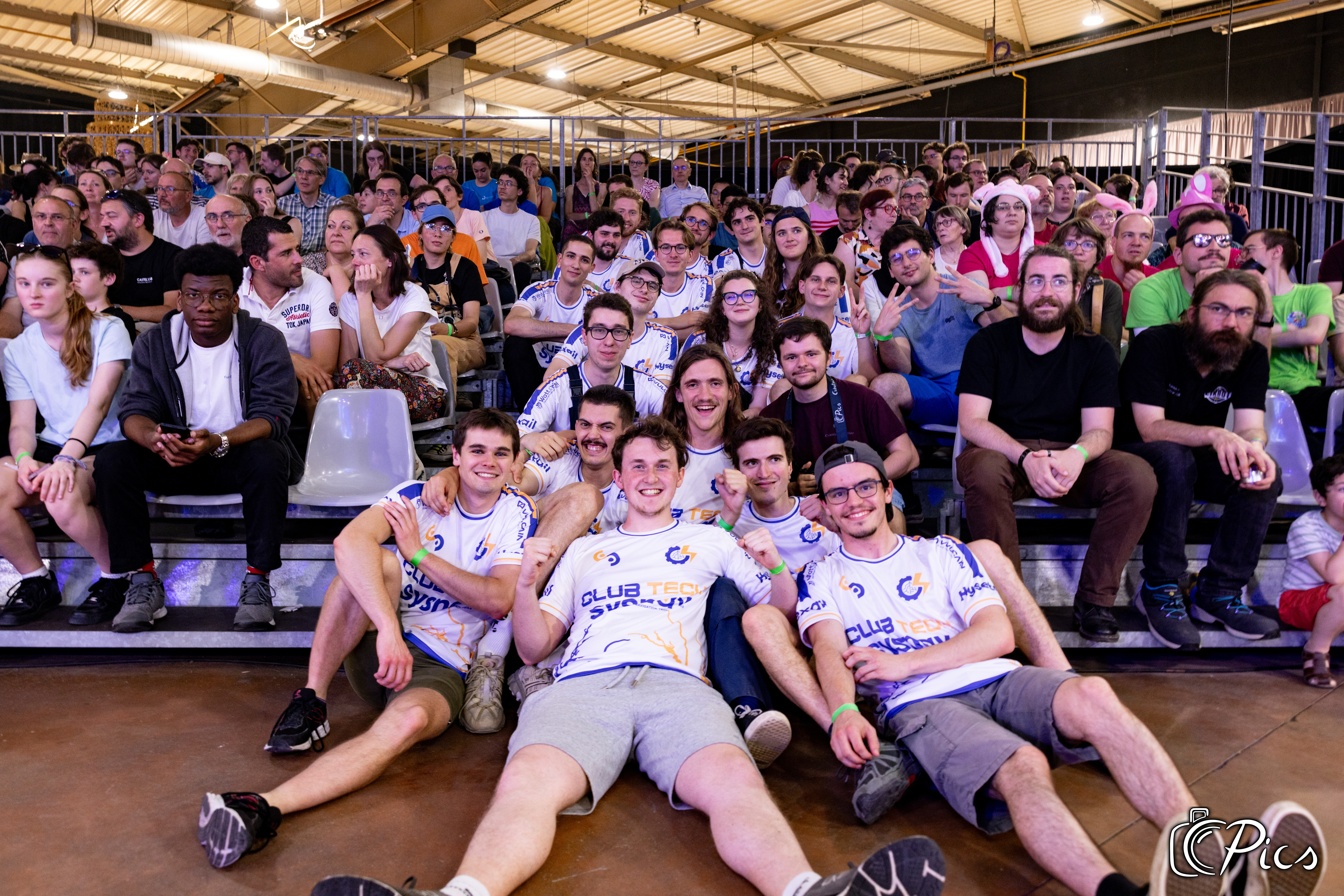 Membres du Club Tech de CentraleSupélec posant ensemble dans les gradins lors de la Coupe de France de Robotique 2025.
